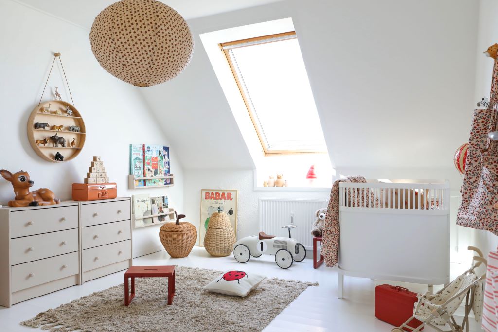 Hyggeligt børneværelse med tremmeseng, legetøj, kommoder og hylder til opbevaring