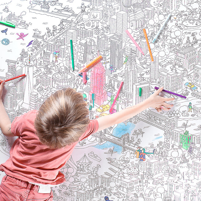 Barn tegner på en stor maleplakat med bymotiv og farveblyanter.